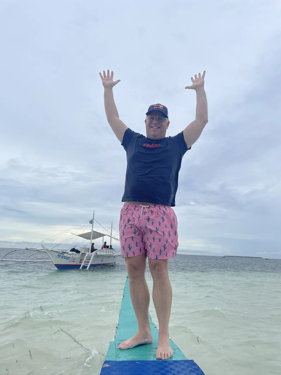 JP Revel celebrating with arms raised on a boat in the Philippines